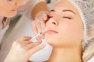 Woman receiving a dental botox injection into her face near her mouth to help remove fine lines.